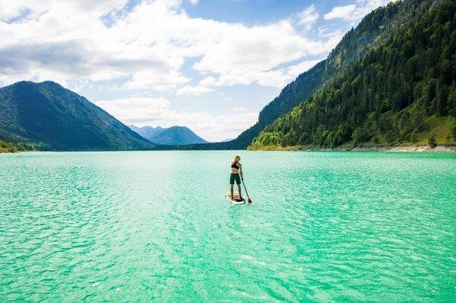 Eine Standup-Paddlerin mitten auf dem von bergen umrahmten Sylvensteinsee., © Tourismus Lenggries|Foto: Adrian Greiter Eine Standup-Paddlerin mitten auf dem von bergen umrahmten Sylvensteinsee., © Tourismus Lenggries|Foto: Adrian Greiter