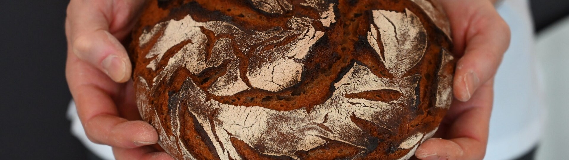 Bäcker, Metzger, das Handwerk - ohne sie alle wäre der Tourismus nicht das, was er ist. Das Bild zeigt einen Laib Brot mit dunkler Kruste in den Händen eines Bäckers., © Kerstin Riemer Bäcker, Metzger, das Handwerk - ohne sie alle wäre der Tourismus nicht das, was er ist. Das Bild zeigt einen Laib Brot mit dunkler Kruste in den Händen eines Bäckers., © Kerstin Riemer