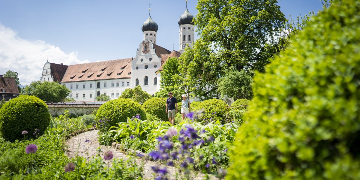 Ein Spaziergang durch den Meditationsgarten vor dem Kloster Benediktbeuern mit seinem beiden markanten Zweibeltürmen., © Tölzer LandTourismus|Dietmar Denger Ein Spaziergang durch den Meditationsgarten vor dem Kloster Benediktbeuern mit seinem beiden markanten Zweibeltürmen., © Tölzer LandTourismus|Dietmar Denger