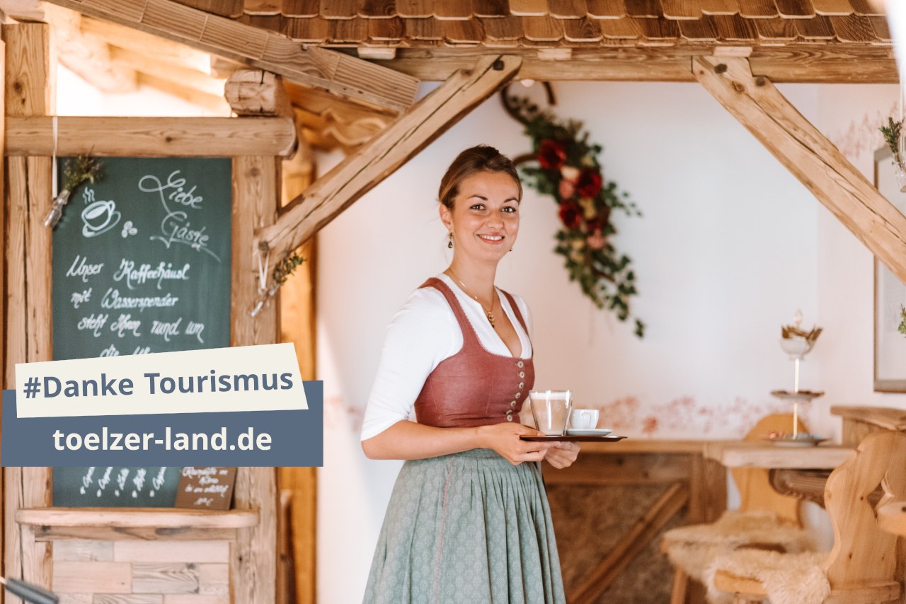 Freundliche Bedienung in Tracht mit Tablett in der Hand., © Tölzer Land Tourismus, Leonie Lorenz Freundliche Bedienung in Tracht mit Tablett in der Hand., © Tölzer Land Tourismus, Leonie Lorenz