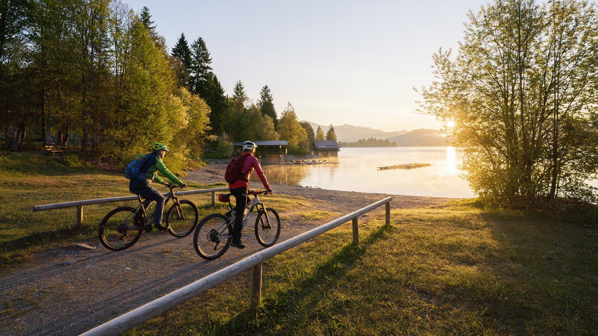 Welch Ausblick auf den Walchensee! Zwei Fahrradfahrer fahren auf den in morgendlichen Sonnenlicht getauchten Walchensee zu., &copy; Archiv T&ouml;lzer Land Tourismus| Foto: Bernd Ritschel