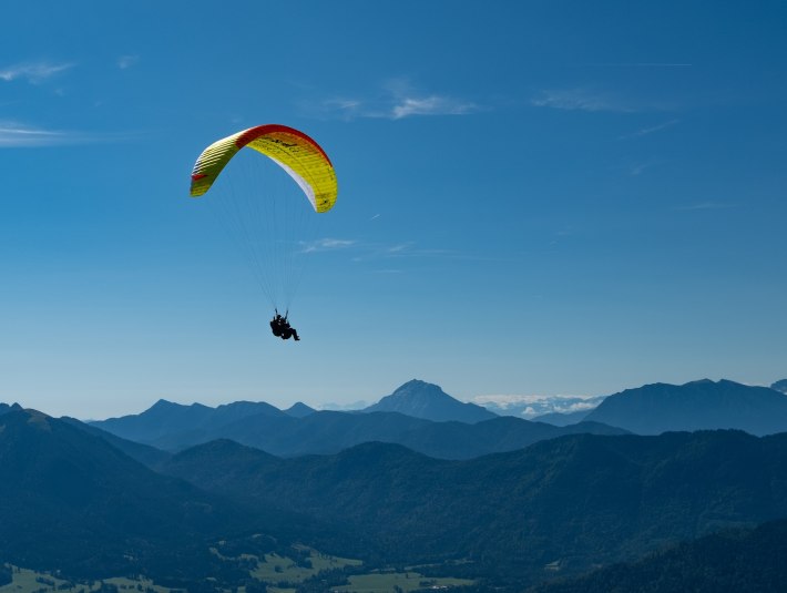 Ein tolles Erlebnis- Gleitschirmfliegen.
Das Bild zeigt einen Gleitschirmflieger &uuml;ber blauen Bergk&auml;mmen; im Hintergrund schneebedeckte Alpen unter klarem Himmel., &copy; Adventure Sports Gbr|Foto: Rafael Frei