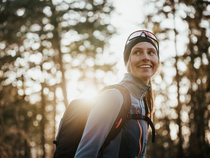 Eine sportlich gekleidete Frau l&auml;chelt gl&uuml;cklich w&auml;hrend sie zum Himmel blickt, &copy; Ooberbayern.de|Aline K&ouml;hler