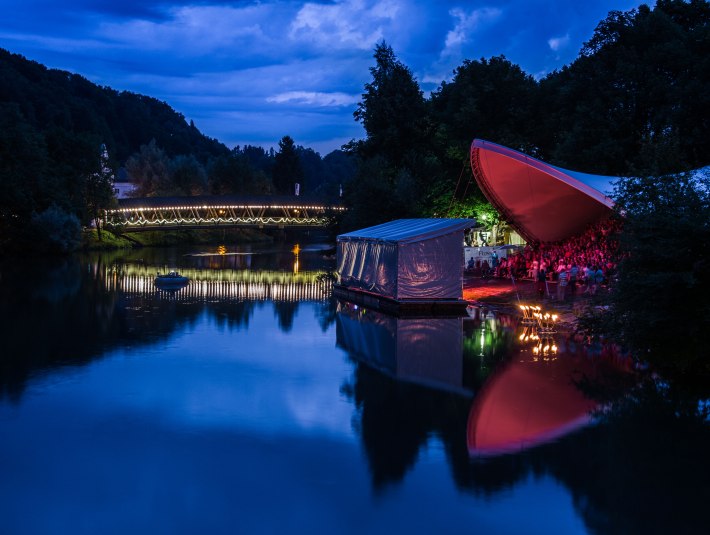 auf dem Bild ist die Loisach im Hintergrund der Sebastianisteg in abendlicher Stimmung an der alten Flosslände ist die Bühne vom Flussfestival zu sehen , © Tom Hirschmann