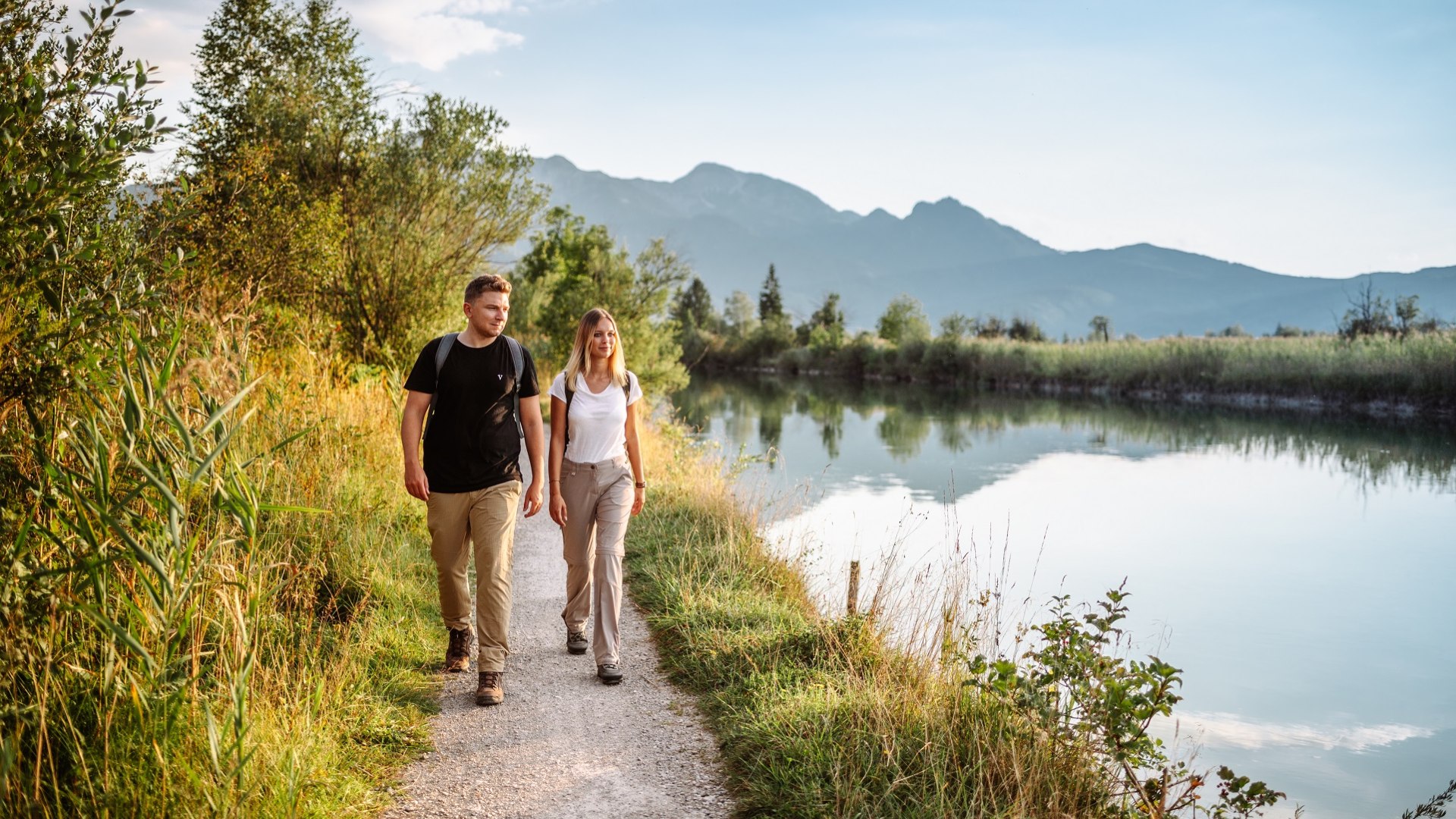 Entspannt wandert  das Parr entlang eines Flusses mit Bergen im Hintergrund., &copy; T&ouml;lzer LAnd Tourismus, Foto: Leonie  Lorenz