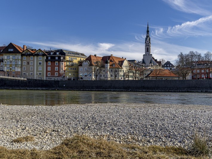 Isarufer mit Kiesstrand im Vordergrund, dahinter die Altstadt von Bad T&ouml;lz mit bunten H&auml;usern und markantem Kirchturm  der Stadtpfarrkirche unter blauem Himmel., &copy; Stadt Bad T&ouml;lz