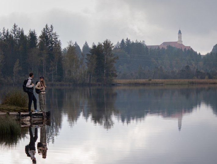 Zwei Wanderer genie&szlig;en den Blick auf Kloster Reutberg oberhalb des Kirchsees, &copy; T&ouml;lzer Land  Tourismus|Christian Geigl