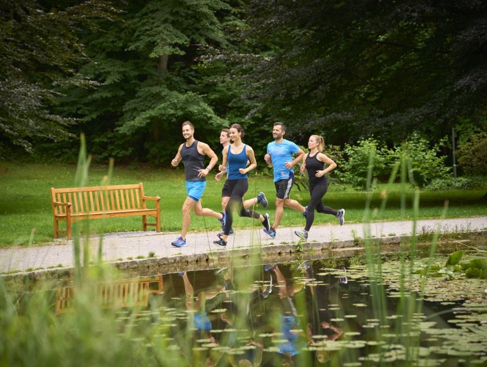 Eine Gruppe Läufer joggt durch den Kurpark von Bad Tölz - das Laufcamp-Angebot im Frühjahr und Herbst 2025 richtet sich an alle die gerne in der Natur unterwegs sind und ihre Laufskills verbessern wollen., © Stadt Bad Tölz