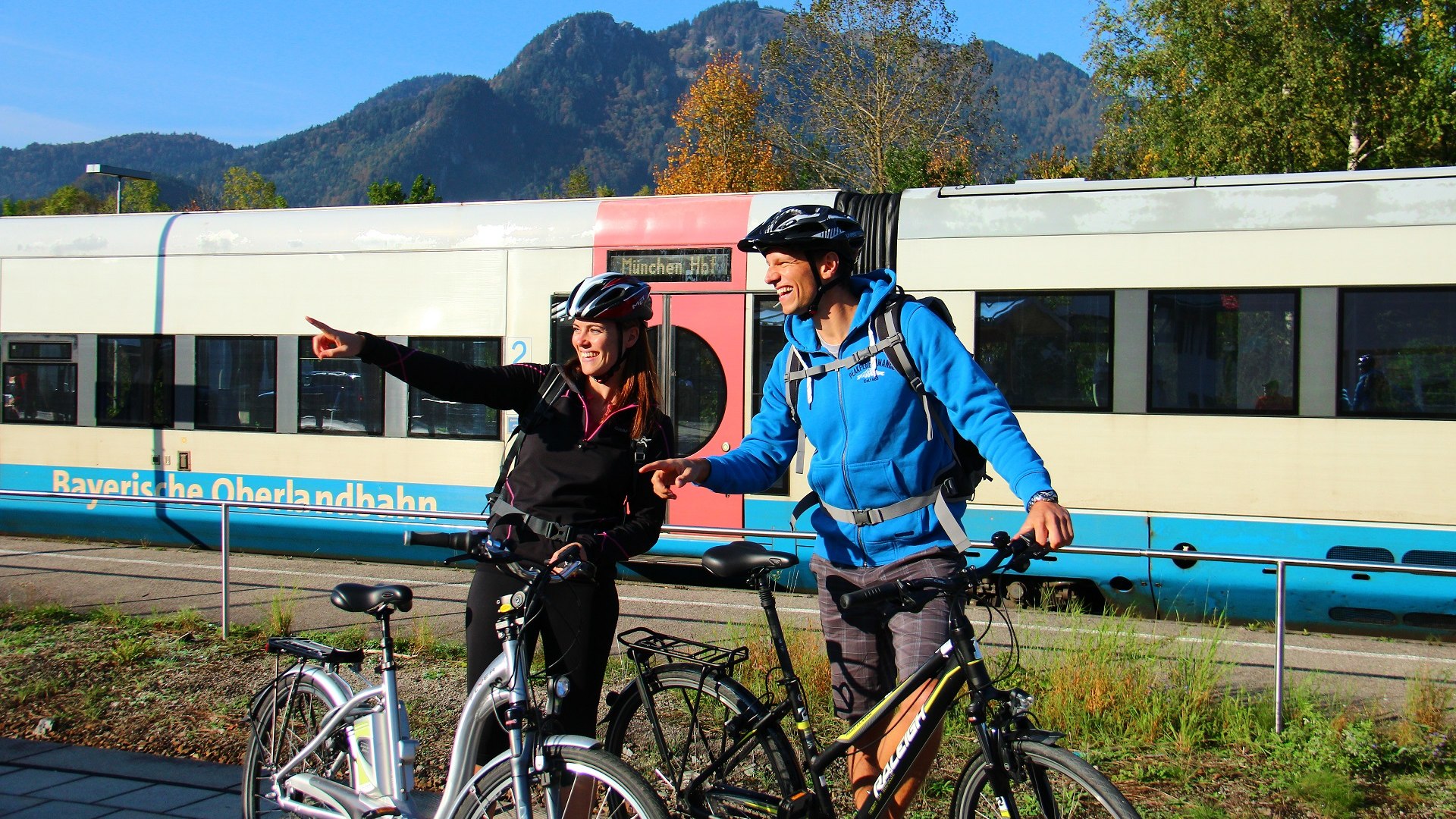 Fahrradfahrer am Lenggrieser Bahnhof mit einem Zug der Bayerischen Oberlandbahn - f&uuml;r sanftes Reisen in den Bayerischen Alpen, &copy; Archiv T&ouml;lzer Land Tourismus|M&uuml;nchen-Venezia