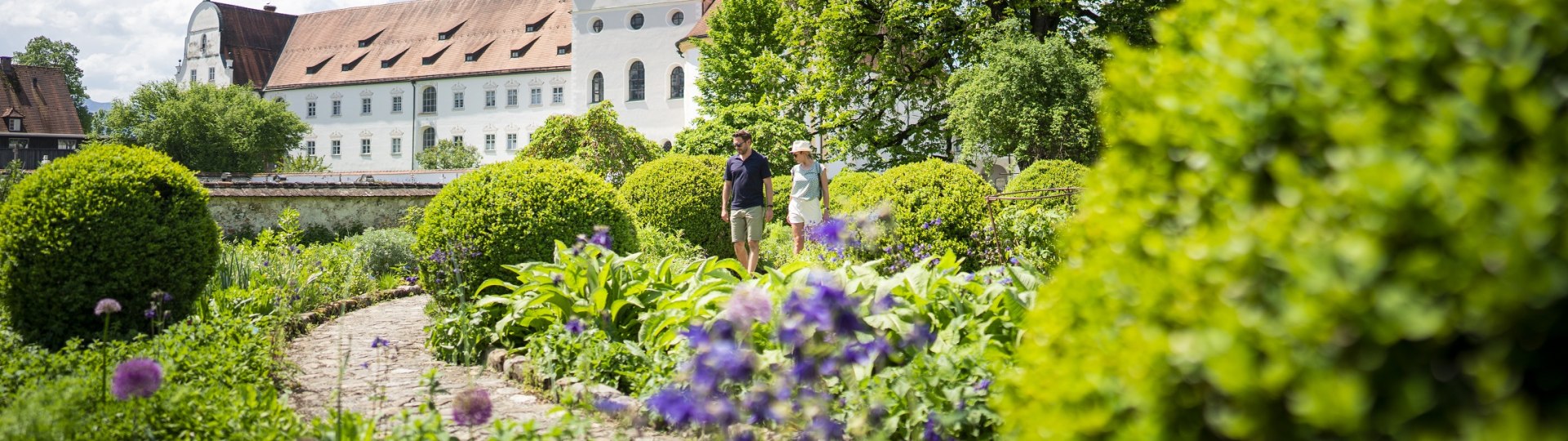 Ein Spaziergang durch den Meditationsgarten vor dem Kloster Benediktbeuern mit seinem beiden markanten Zweibeltürmen., © Tölzer LandTourismus|Dietmar Denger
