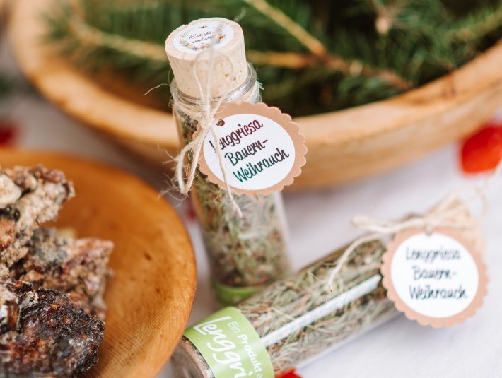 Das Bild zeigt zwei kleine Glasfläschchen mit getrockneten Kräutern, beschriftet mit „Lenggrieser Bauernweihrauch“, auf einem weißen Tuch, im Hintergrund ein Korb., © Tölzer Land Tourismus|Leonie Lorenz