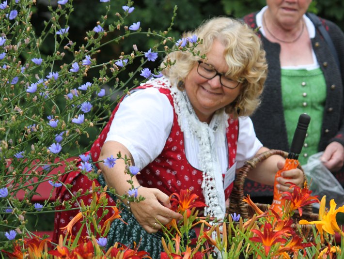Kräuterpädagogin Anneliese Stockinger zeigt im Kräuter-Erlebnis-Park Bad Heilbrunn zeigt bei eine Park-Führung essbare Blüten wie z.B. die Taglilie, © Tölzer Land Tourismus|Kirschenhofer