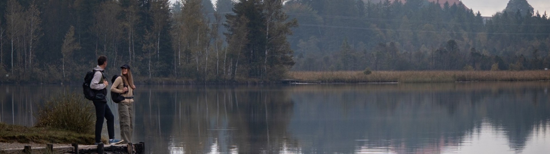 Zwei Wanderer genießen den Blick auf Kloster Reutberg oberhalb des Kirchsees, © Tölzer Land Tourismus|Chris Reigl