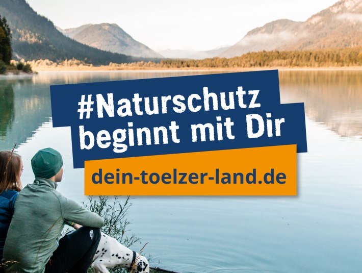 Die Natur ist Dir wichtig? Das Infoportal auf www.dein-toelzer-land.de  informiert und klärt auf.
Das Foto zeigt in herbstlicher Stimmung ein Pärchen mit einem schwarz gepunkteten Hund an einem See sitzend. Über dem Foto ist das Logo der Naturschutzkampagne mit der Aufschrift &quot;Naturschutz beginnt mit Dir&quot;, © Tölzer Land Tourismus|Foto: L. Hartung