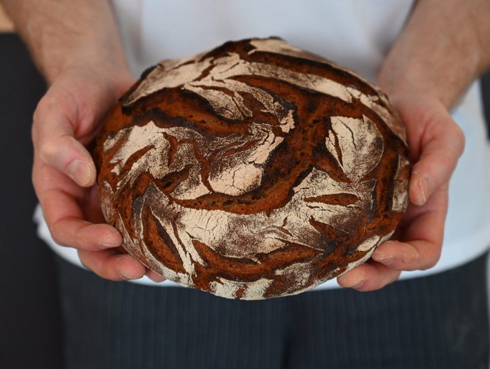 Bäcker, Metzger, das Handwerk - ohne sie alle wäre der Tourismus nicht das, was er ist. Das Bild zeigt einen Laib Brot mit dunkler Kruste in den Händen eines Bäckers., © Kerstin Riemer