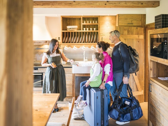 Das Bild zeigt eine Rezeption, bei der gerade eine Familie anreist., © Tölzer Land Tourismus|Dietmar Denger