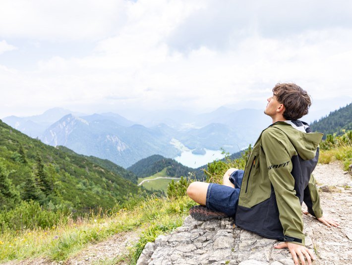 Naturgenuss. Mann sitzt auf Fels und blickt in die Berg- und Seenlandschaft im T&ouml;lzer Land, &copy; Farmhouse7